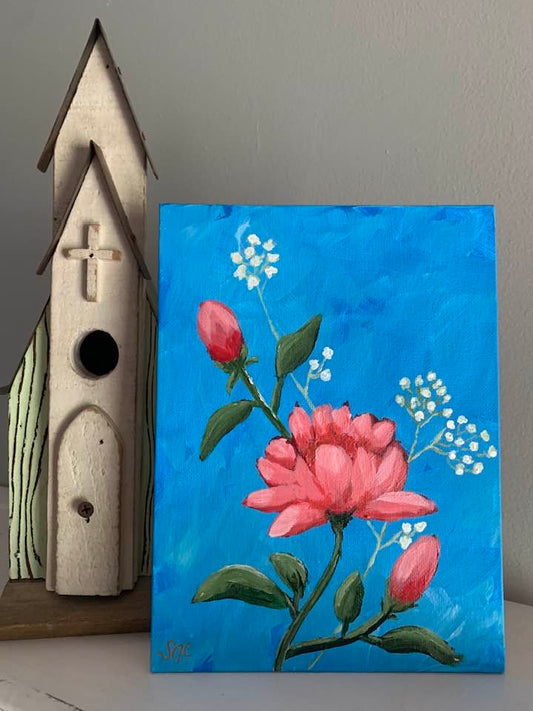 A painting with blue background, red roses and baby's breath sitting next to a birdhouse.